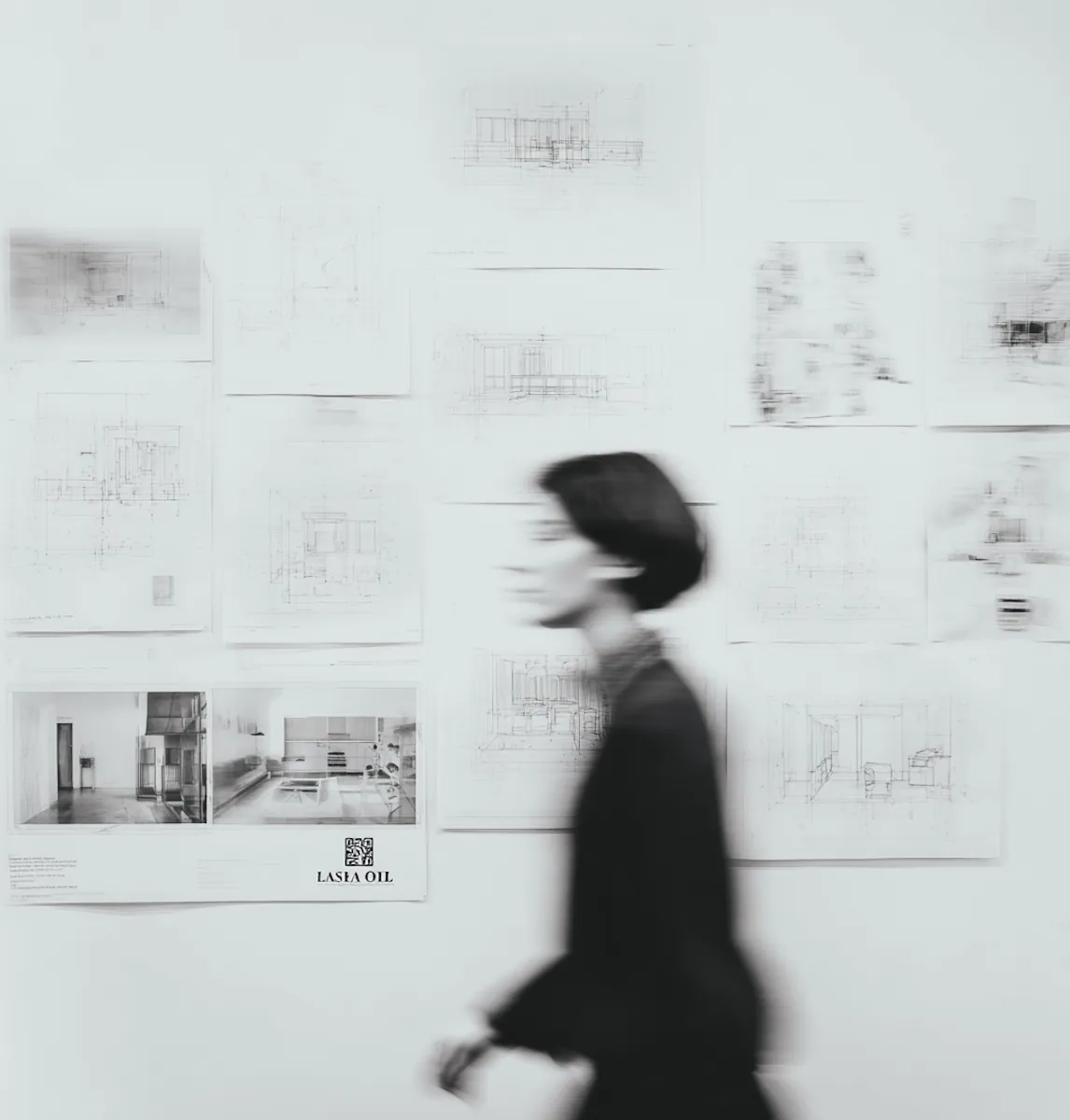 A designer walking past a wall of page layouts and sketches